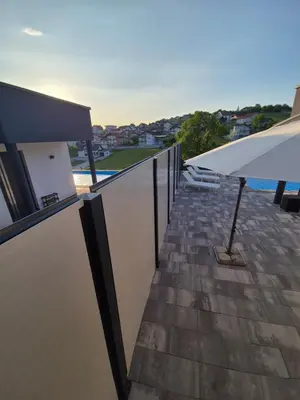 a balcony with a white umbrella and a pool at Apartmani City ES in Cazin