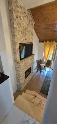 a living room with a stone fireplace and a tv at Viktory in Vlasic