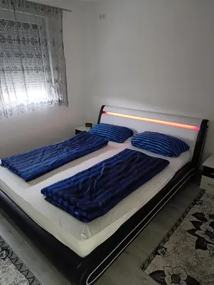 two beds in a bedroom with blue sheets and pillows at Apartman Ella in Bosanska Krupa