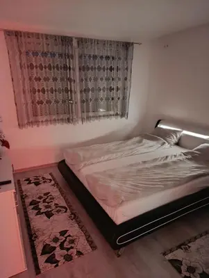 a bed in a bedroom with a window and a rug at Apartman Ella in Bosanska Krupa