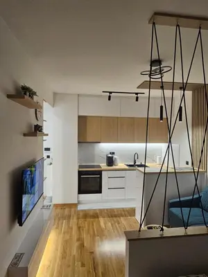 a kitchen with white cabinets and a blue chair at Apartment Shine - Borik in Banja Luka