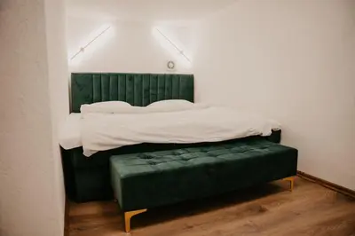 a bed with a green bench in a room at Zapato Apartment Tuzla in Tuzla
