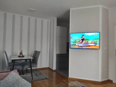 a living room with a tv on a wall at Apartman Luka in Doboj