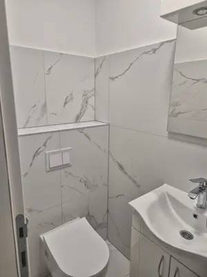 a white bathroom with a toilet and a sink at Apartmans Zenica in Zenica
