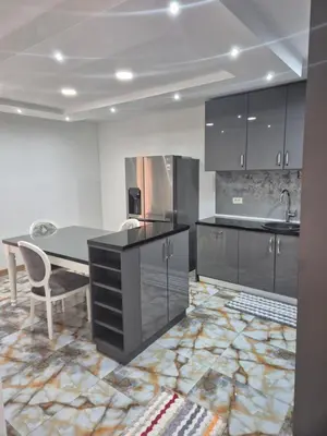 a kitchen with black cabinets and a table and a sink at Apartmans Zenica in Zenica