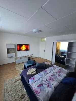 a bedroom with a large bed and a living room at Apartman Lea in Železnička Stanica Incel