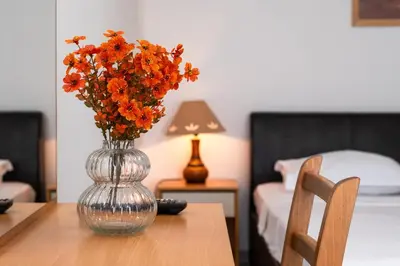 a glass vase with orange flowers sitting on a table at Motel Jelić in Kraševo