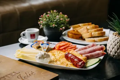 a plate of breakfast food with eggs sausage and cheese at Motel Jelić in Kraševo