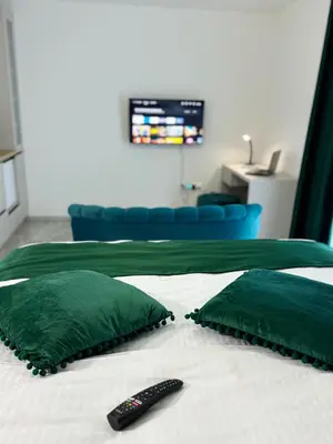 a bed with two green pillows and a remote control at Apartmani Ikanović in Cazin