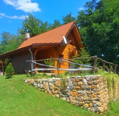 a log cabin with a stone wall in front of it at Kuca za odmor in Vitez