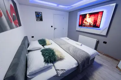 a bedroom with a bed with a tv on the wall at Heaven Heart - Apartmani Tuzla in Tuzla