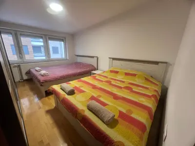 a bedroom with two beds and two windows at Apartman King centar in Banja Luka