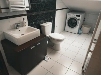 a bathroom with a sink toilet and a washing machine at Apartman King centar in Banja Luka