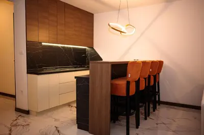 a kitchen with a counter and some brown chairs at Apartmani VIZIJA in Visoko
