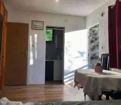 a living room with a table and a kitchen at Studio apartman VB in Banja Luka