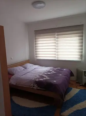 a bedroom with a bed and a window with blinds at VA Apartmani Živinice in Živinice