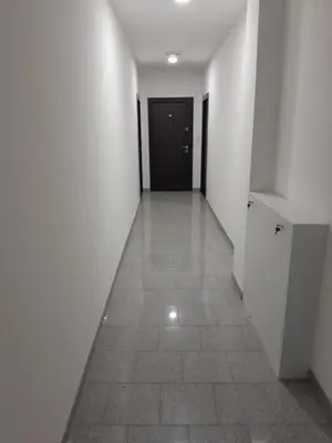 a hallway with white walls and a tile floor and a black door at VA Apartmani Živinice in Živinice