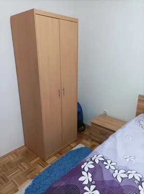 a bedroom with a wooden cabinet and a bed at VA Apartmani Živinice in Živinice