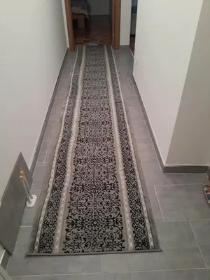 a hallway with a black and white rug on the floor at VA Apartmani Živinice in Živinice