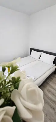 a bedroom with a bed with white sheets and flowers at Apartman Mima in Sanski most