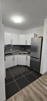 a kitchen with white cabinets and a stainless steel refrigerator at Apartman Mima in Sanski most