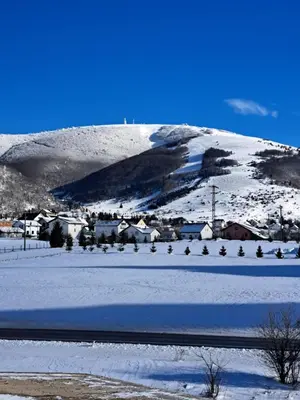 a snow covered mountain with a town in the foreground at Apartman Mika in Kupres