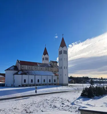 a large white building with two towers in the snow at Apartman Mika in Kupres