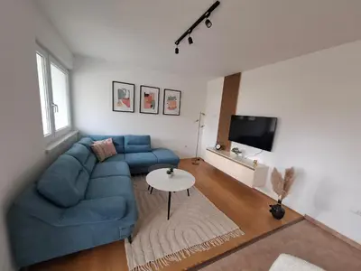 a living room with a blue couch and a table at Apartman Mika in Kupres