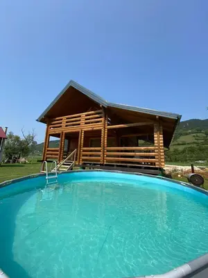 a large swimming pool in front of a log cabin at Vikendica ANA in Šipovo