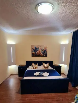a bedroom with a large bed with a blue bedspread at Genex-M in Bugojno