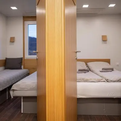 a door to a room with two beds and a window at Ćuranov rep in Mrkonjić Grad