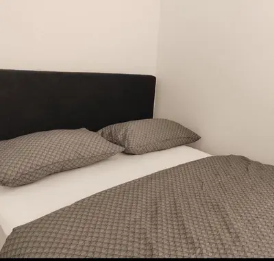 a bed with two pillows and a black headboard at Stan na dan Modriča in Modriča