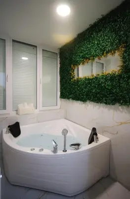 a bathroom with a bath tub with a green wall at Gold Luxury Apartment in Bosanska Gradiška