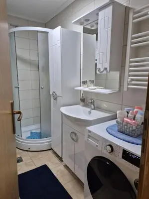 a white bathroom with a shower and a washing machine at Studio Apartment Borik 19 in Banja Luka