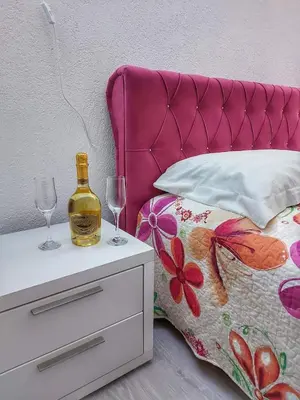 a bed with a bottle of wine on a night stand at Stan na dan Gabriella in Prijedor