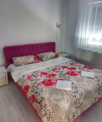 a bedroom with a bed with a pink headboard at Stan na dan Gabriella in Prijedor