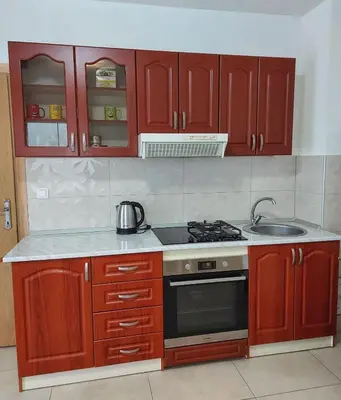 a kitchen with wooden cabinets and a stove top oven at Stan na dan Gabriella in Prijedor