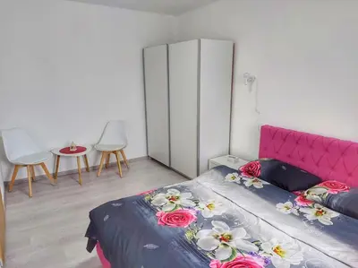 a bedroom with a pink bed and a table and chairs at Stan na dan Gabriella in Prijedor