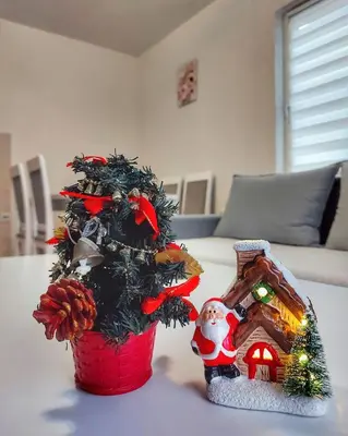 a christmas tree and a miniature house on a table at Stan na dan Gabriella in Prijedor