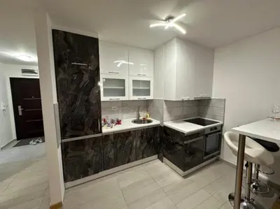 a kitchen with white cabinets and black marble counter tops at Apartman Mia in Doboj