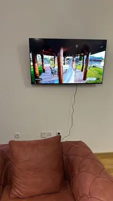 a flat screen tv hanging on a wall above a couch at Apartman Mia in Doboj