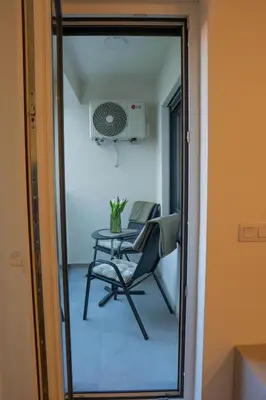 a glass door leading into a room with a table and a chair at Apartment OMEGA in Banja Luka