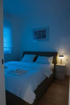 a blue bedroom with a large bed with white sheets at Apartment OMEGA in Banja Luka