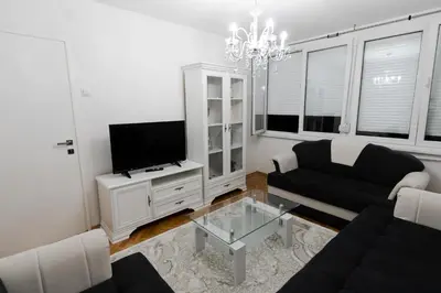 a living room with a black couch and a tv at Tanja in Banja Luka