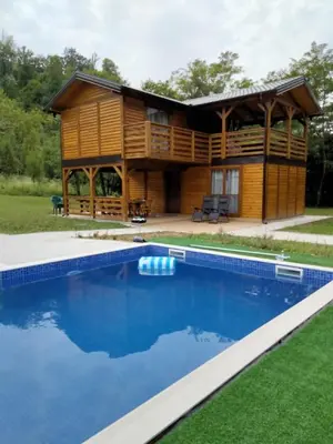 a log house with a pool in front of it at Vikendica Čardak in Srebrenik