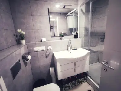 a bathroom with a sink and a toilet and a mirror at Apartman Luxe in Livno