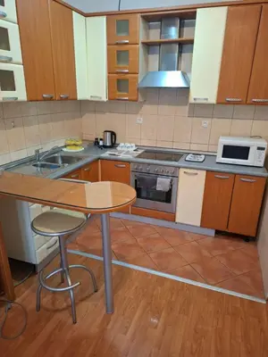 a kitchen with wooden cabinets and a wooden table at Mia lux centar in Banja Luka