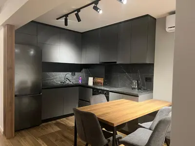 a kitchen with a wooden table and black cabinets at Aleja bb apartment in Banja Luka