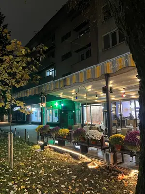 a building with tables and chairs in front of it at night at Aleja bb apartment in Banja Luka