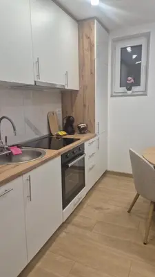a kitchen with white cabinets and a sink and a table at Bella Vacanza Apartment in Banja Luka